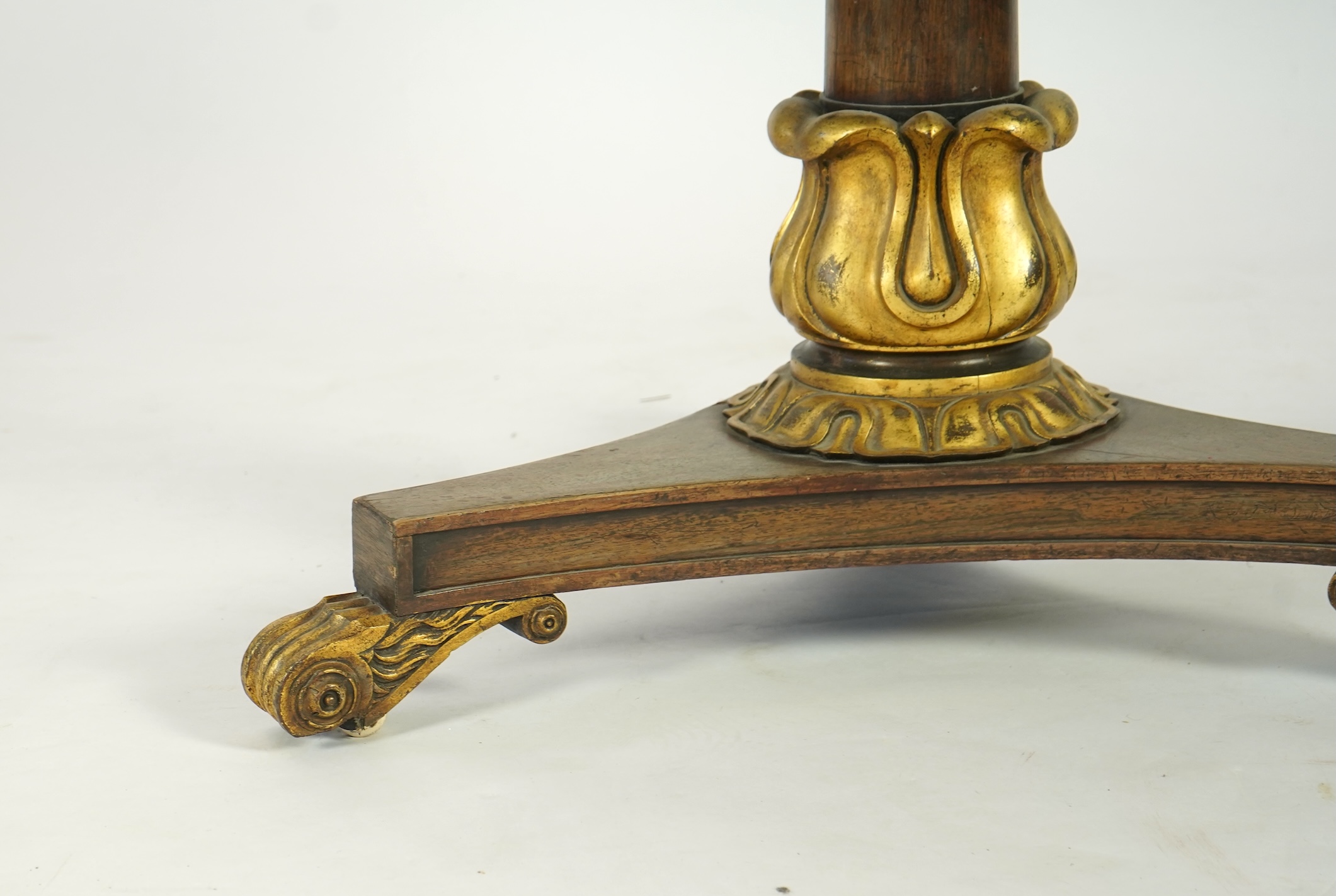 A George IV parcel gilt mahogany circular slate top centre table